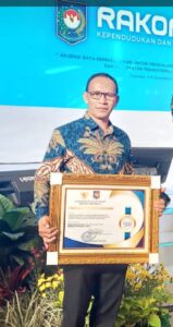 Kadis Dukcapil Mabar, Valentinus Andi dan Piagam Penghargaan Dukcapil Prima Award. (Foto : Ist.)