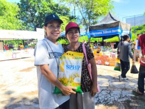 Ibu Viktoria (kanan) dan Ibu Kristin saat menenteng beras yang dibeli di pasar murah. (Foto : Tildis) 