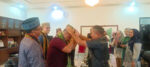 Bupati Edi (kanan) saat mengalungkan selendang dan topi Manggarai. (foto : Rafika)